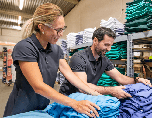 bulkpricing Workers folding shirts in a warehouse for an embroidery business